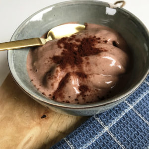 Chocolade proteine smoothie bowl op houten plank met gouden lepel