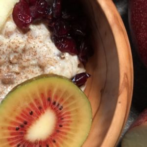 Houten kom havermout met stukjes appel, kiwi en granaatappel