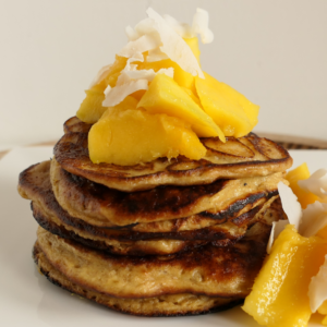 Stapeltje protein pancakes met stukken mango en kokos op bord