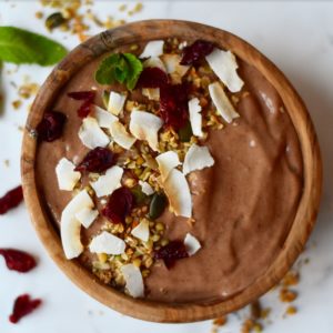 houten kom met chocolade nicecream, gedecoreerd met kokosvlokken, cranberries, munt en nootjes